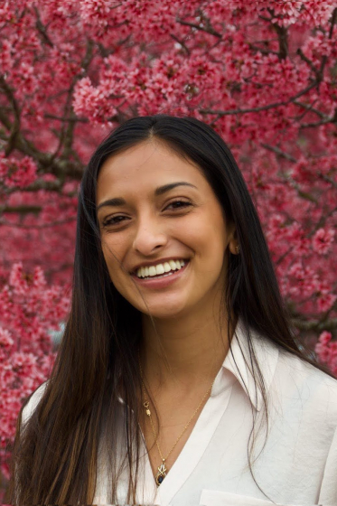 headshot of Ritika in white with pink flowers in background